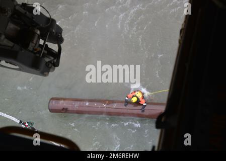 La vue de la trappe inférieure d’un CH-47 Chinook affecté à la Compagnie Bravo de la Garde nationale de l’Armée de New York, 3rd Bataillon, 126th Aviation montre un membre de l'équipe de sauvetage en haute mer de la police du parc de l'État de New York qui fixe un câble de levage à un ponton en acier de 3 900 livres dans la rivière Niagara, juste au-dessus du côté américain des chutes du Niagara, à Niagara Falls, dans l'État de New York, sur 4 mai 2022. Le ponton, qui s'est éloigné d'un barrage de glace en 2019, a été levé par le CH-47 et déplacé à l'île Goat. Il a été enlevé en raison de préoccupations qu'il pourrait dépasser les chutes et endommager la “grotte des vents”. ( U. Banque D'Images