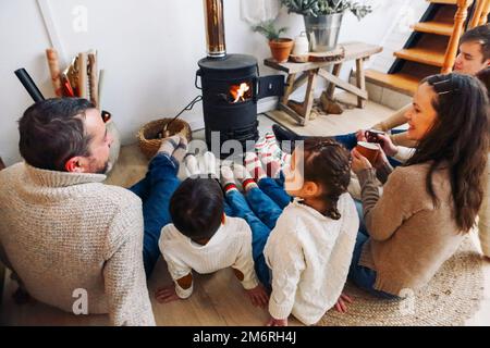 Photo courte de la grande famille portant des chaussettes chaudes en laine reposant au coin de la cheminée en hiver. Mère Banque D'Images