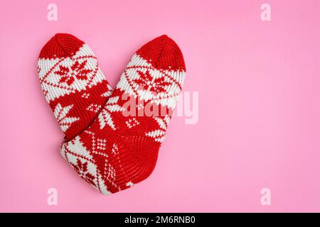 Chaussettes tricotées pliées en forme de coeur sur fond rose. Saint Valentin. Arrière-plan de vacances Banque D'Images