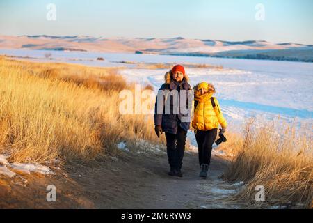 Couple romantique de touristes vêtus de vêtements de sport chauds d'hiver avec des sacs à dos touristiques marchant dans la neige Banque D'Images