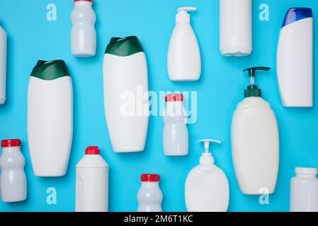 Bouteilles blanches en plastique vides pour cosmétiques et autres substances liquides sur fond bleu. Blanc pour gel de marquage, shampooing, mise Banque D'Images