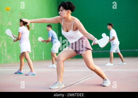 Femme servant le ballon pendant le jeu frontenis à l'extérieur Banque D'Images