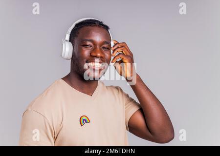étudiant hispanique avec badge arc-en-ciel sur le t-shirt en studio isoler écouter de la musique Banque D'Images