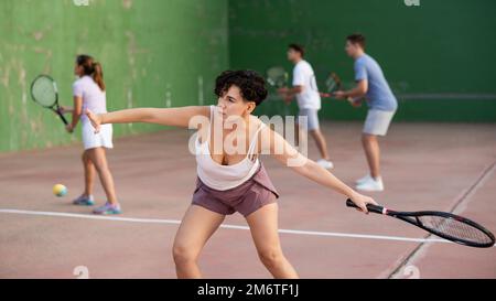 Femme sportive en short et t-shirt jouant frontenis sur le terrain Banque D'Images