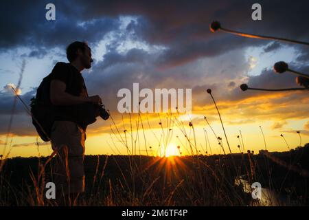 Un jeune homme qui séjourne et regarde le coucher du soleil. Paysage d'été lumineux et ensoleillé. Voyager en Ukraine Banque D'Images