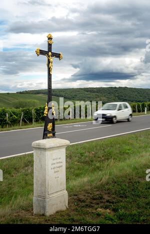 Croix religieuse près d'une route avec voiture Banque D'Images