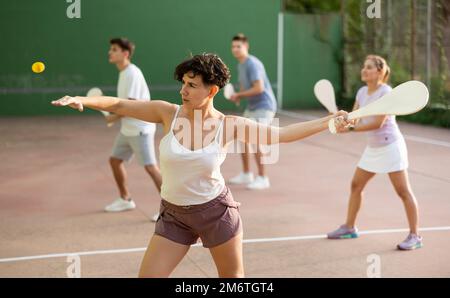 Femme servant le ballon pendant le jeu frontenis à l'extérieur Banque D'Images