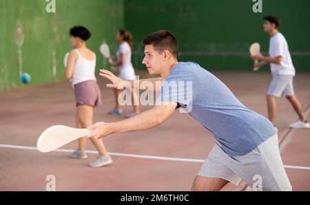 Jeune homme servant le ballon pendant le jeu de pelota à l'extérieur Banque D'Images