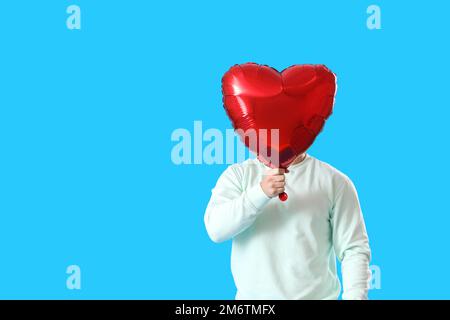 Jeune homme avec ballon pour la Saint-Valentin sur fond bleu Banque D'Images