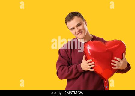 Jeune homme avec ballon pour la Saint-Valentin sur fond jaune Banque D'Images