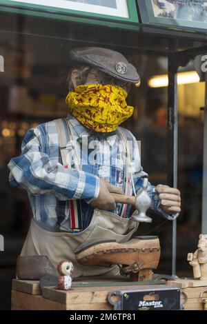 Un vieux mannequin publicitaire motorisé dans une fenêtre d'atelier de réparation de chaussures à Kelso, en Écosse - un modèle de cobbler avec marteau mobile Banque D'Images