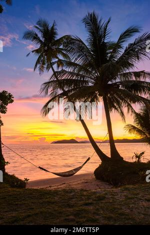Coucher de soleil sur la plage avec palmiers et hamac, île de Koh Mak en Thaïlande Banque D'Images