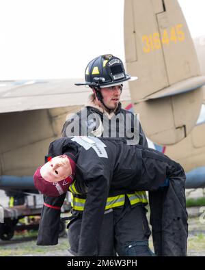 Un pompier de l'escadron du génie civil 788th transporte une victime factice à la sécurité, 5 mai 2022, lors d'un exercice de victimes massives à la base aérienne Wright-Patterson, en Ohio. L'exercice comportait un accident d'avion factice et a donné aux premiers intervenants l'occasion de s'exercer à coordonner les procédures d'intervention d'urgence. Banque D'Images