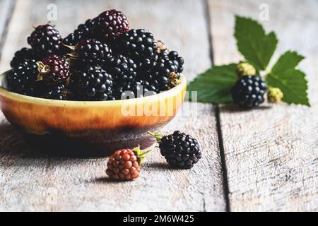 mûre fraîche dans un bol sur table en bois, fruits mûrs et feuilles vertes, espace de copie Banque D'Images