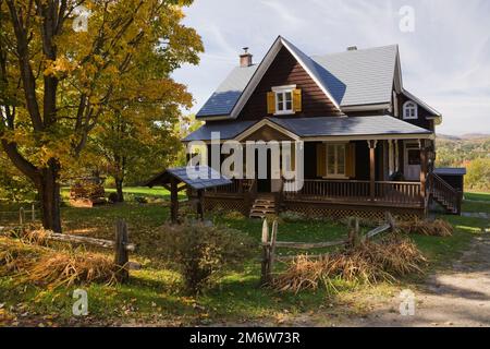 Ancienne planche de bois brun 1877 ajoutée avec garniture blanche et jaune maison de style cottage avec Acer - Maple Tree en automne. Banque D'Images