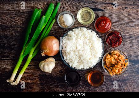 Riz frit Kimchi Ingrédients sur une table rustique en bois : riz cuit, chou fermenté et autres ingrédients et condiments Banque D'Images