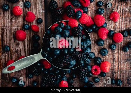 Bleuets, framboises et mûres dans une tasse à mesurer : mélange de trois types de baies fraîches dans une tasse à mesurer en métal Banque D'Images