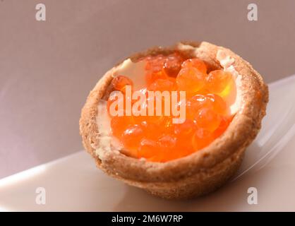 Tartelette au caviar rouge sur une assiette blanche, friandises festives en gros plan Banque D'Images