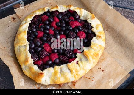 Galette de baies fraîchement cuite sur un poêle à papier parchemin : tarte rustique au dessert faite avec des framboises, des bleuets et des mûres Banque D'Images