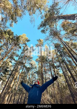 Voyageur homme dans un blouson d'hiver bleu annonce casquette rouge dans les bois. Baie de sable, lac Baikal Banque D'Images