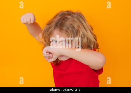 Andry boy en t-shirt rouge faisant un geste d'arrêt sur un arrière-plan de studio isolé. Enfant montrant le symbole d'avertissement, le symbole de la main n° Enfant avec le combat gestuel poing. Banque D'Images