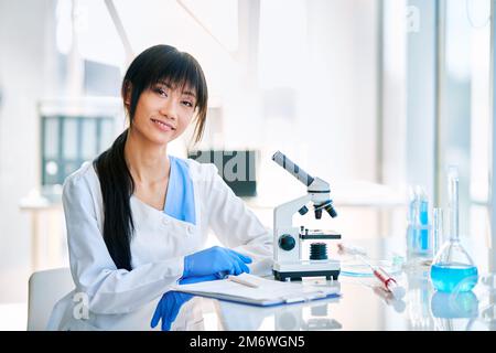 Une scientifique asiatique souriante pose dans un laboratoire de recherche médicale moderne Banque D'Images