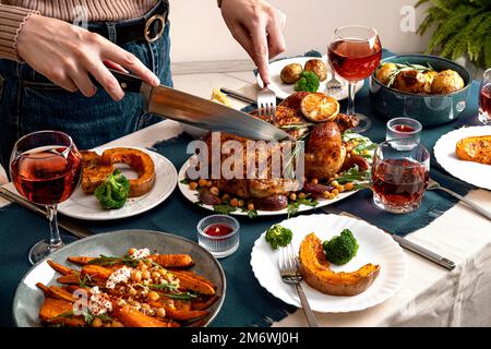 Personnes célébrant le jour de Thanksgiving. Femme qui coupe de la viande pour sa famille et ses amis à table. Poussin traditionnel farci de vacances Banque D'Images