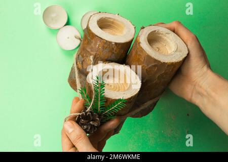 Porte-bougie de Noël à fabriquer soi-même en rondins de pin, bougies, corde d'artisanat, branches de sapin et cônes. Les mains à Banque D'Images