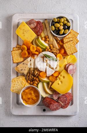 Différents types de fromages et de viandes froides. Vue de dessus sur fond blanc. Assortiment de fromages aux noix, craquelins, olives, sa Banque D'Images