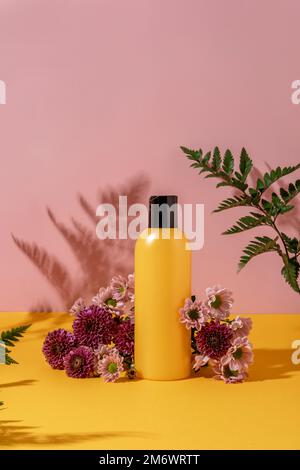 Style d'été de vitrine pour les produits cosmétiques exposition sur fond jaune et rose avec des fleurs. Bouteille jaune cosmétiques produ Banque D'Images