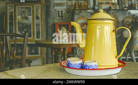 Un plateau de thé placé sur une table ronde se compose d'une théière et de 3 tasses en céramique avec des arrière-plans rustiques isolés de salon de thé et des chemins d'écrêtage. Banque D'Images