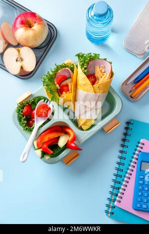 Boîte à lunch scolaire pour enfants avec sandwich, légumes, eau et papeterie sur table. Concept de saines habitudes alimentaires. Retour à la goélette Banque D'Images