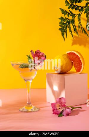 Cocktail de séltzer dur aux saveurs de baies garnies de fleurs d'alstroemeria. Boisson d'été colorée et rafraîchissante sur fond jaune Banque D'Images