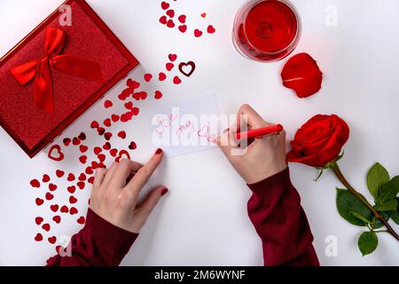 Femme écrivant la lettre d'amour pour la Saint Valentin. Les femmes écrivent la lettre d'amour à la réception, vue du dessus Banque D'Images