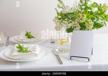 Maquette de carte d'espace blanc pour le numéro de table ou le menu. Décoration de mariage avec fleurs blanches, verres et serviettes blanches. Banque D'Images