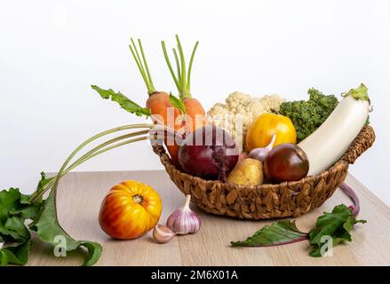 Récolte fraîchement botte. Légumes frais de la ferme dans un panier en osier. Aliments biologiques sains, carottes crues, betteraves, pommes de terre et tomates Banque D'Images