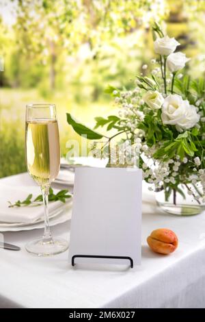 Maquette de carte d'espace blanc pour le numéro de table ou le menu. Décoration de mariage avec fleurs blanches, verres et serviettes blanches. Banque D'Images