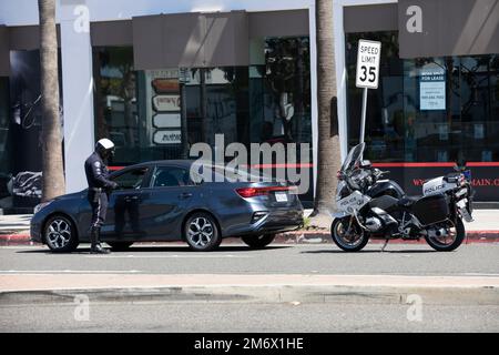 Costa Mesa, Californie, Etats-Unis - 20 mars 2022: Un policier de la cop de moto tire sur un automobiliste pendant un arrêt de circulation. Banque D'Images