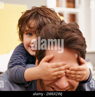 Devinez qui. un petit garçon couvrant les yeux de ses pères avec ses mains. Banque D'Images