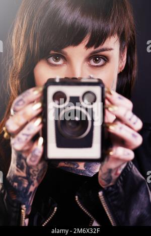 Vous avez été encadré. Photo en studio d'une jeune femme tatouée portant un appareil photo d'époque. Banque D'Images
