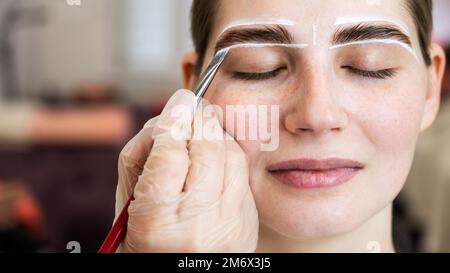 Le maître dessine la forme des sourcils avec de la peinture blanche avant de colorer. Banque D'Images