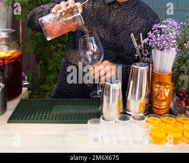 Verres de cocktails au bar. Le barman verse un verre de vin mousseux avec de l'alcool rouge. Banque D'Images