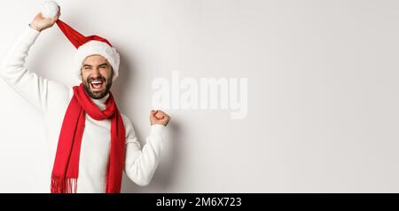 Les vacances d'hiver et le concept de fête du nouvel an. Joyeux Noël dansant en chapeau de père Noël et foulard rouge, debout contre Banque D'Images