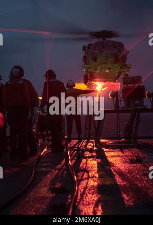 Les marins DU réseau WAN SAGAMI (9 mai 2022) à bord du destroyer de missile guidé de classe Arleigh Burke USS Milius (DDG 69) conduisent un hélicoptère en vol en ravitaillant avec un hélicoptère MH-60s « Seahawk » affecté aux « faucons dorés » de l’Escadron de combat en mer (HSC) 12. Milius mène actuellement des opérations de routine dans le domaine de responsabilité de la flotte 7th aux États-Unis. Banque D'Images