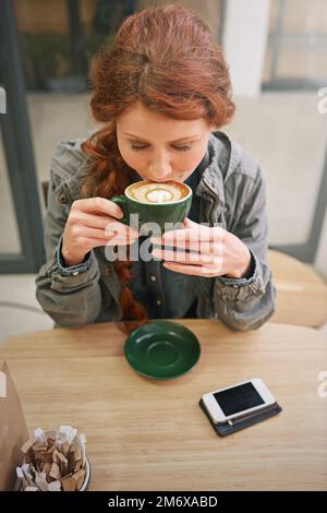 Elle aime l'arôme. une jeune femme boit son cappuccino dans un café. Banque D'Images