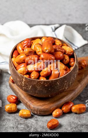 Fruits frais crus aux limelles sur fond sombre. Silverberry dans un bol de noix de coco. Oleaster ou olive russe (Elaeagnus). gros plan Banque D'Images