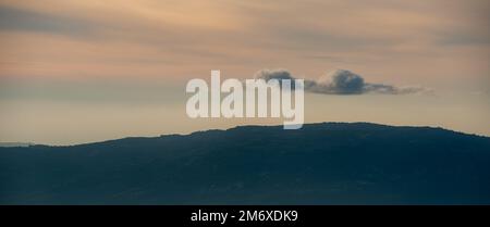 Silhouette de pics de montagne avec brouillard et nuages spectaculaires. Coucher de soleil coloré. Banque D'Images