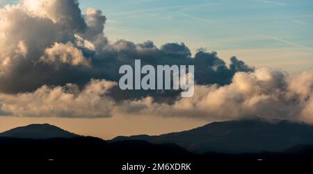 Silhouette de pics de montagne avec brouillard et nuages spectaculaires. Coucher de soleil coloré. Banque D'Images