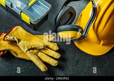 gants écouteurs casque et boîte à outils sur fond noir Banque D'Images