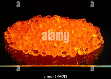 Caviar de saumon doré brillant sur une plaque de verre Banque D'Images